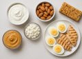 Assorted high-protein snacks including nuts, yogurt, eggs, and protein bars on a kitchen counter