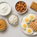 Assorted high-protein snacks including nuts, yogurt, eggs, and protein bars on a kitchen counter