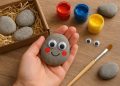 Hand-painted pet rock with googly eyes and colorful decorations on a wooden surface